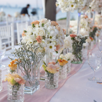 A long table with many flowers set for a special occasion.