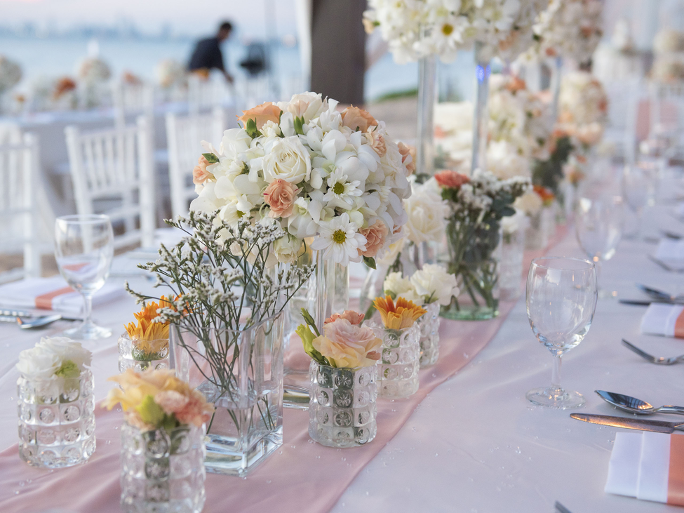 A long table with many flowers set for a special occasion.