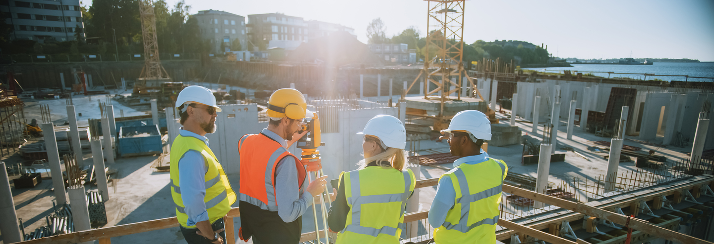 A group of construction workers stand on a platform overlooking a jobsite.