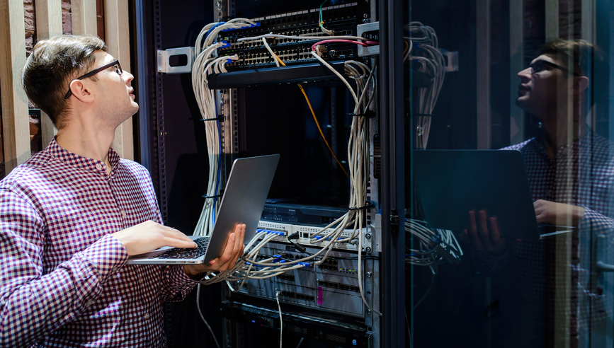 Engineer inspecting a server rack with cables.