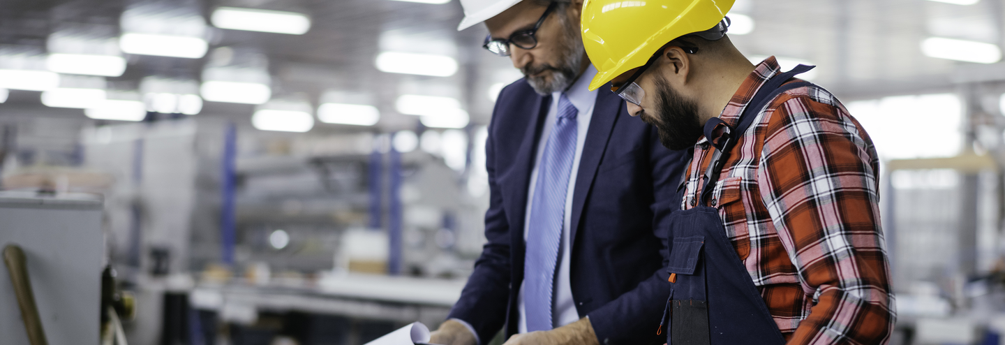 An engineer meets with a quality control inspector in a factory.