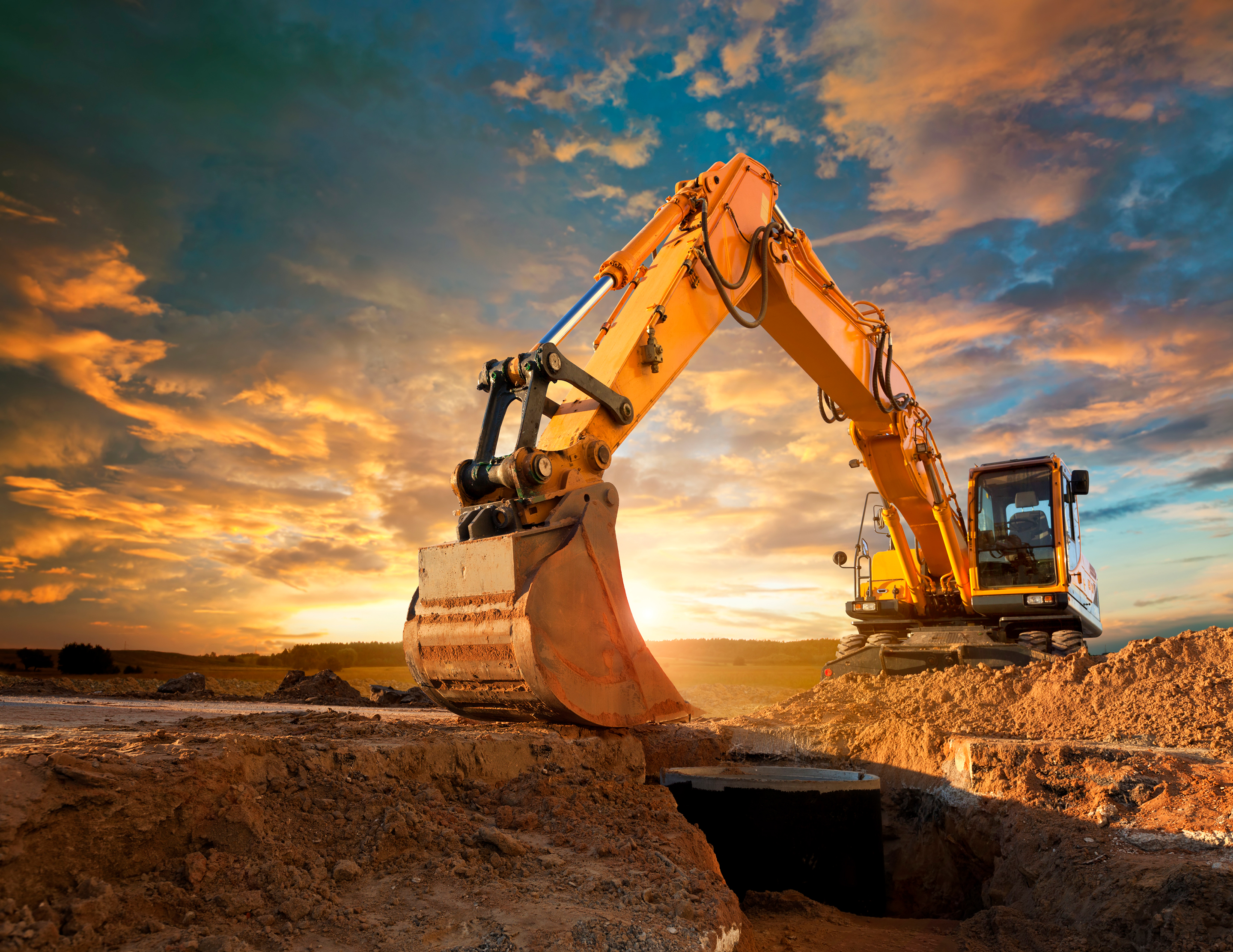 Excavator at a construction site against the setting sun.