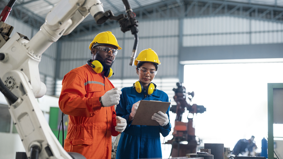 Factory workers near robotic arm.