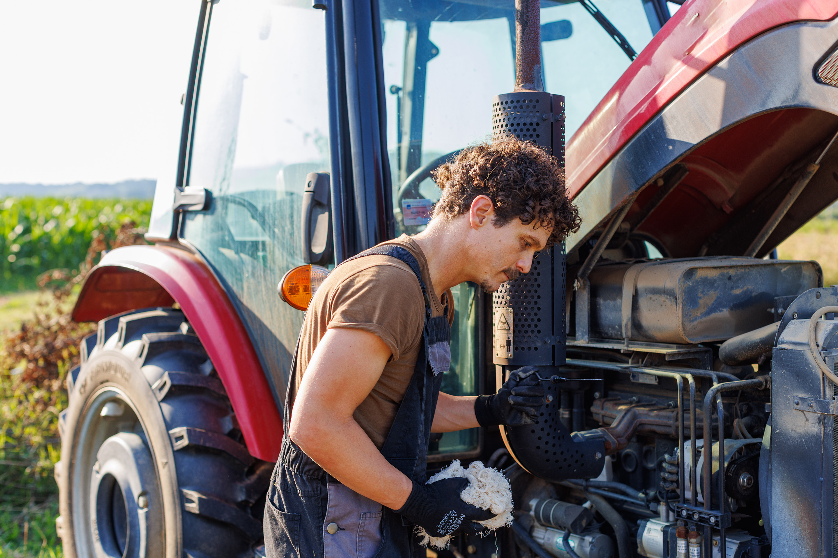 A farmer performs maintenance on his tractor on a farm. 