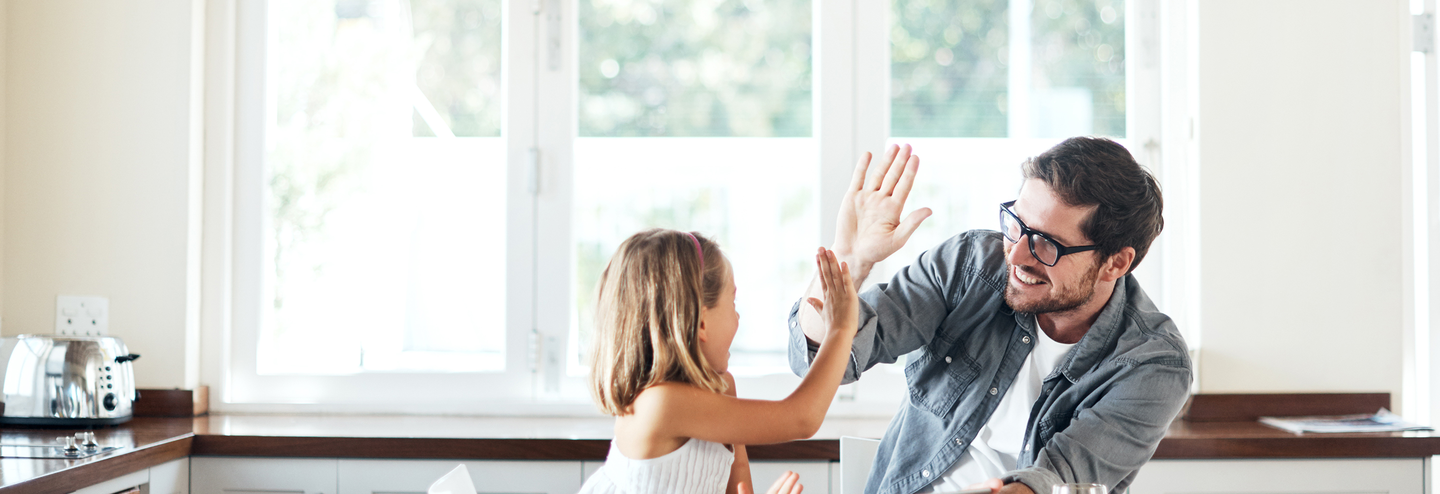 Man and child give each other a high five in a kitchen