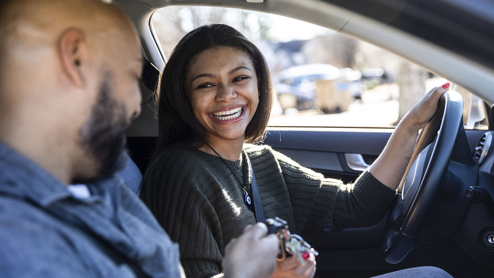 Young woman driving with middle-aged man in the passenger seat.