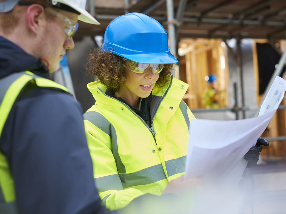 Project owners examine draft plans at a construction site.