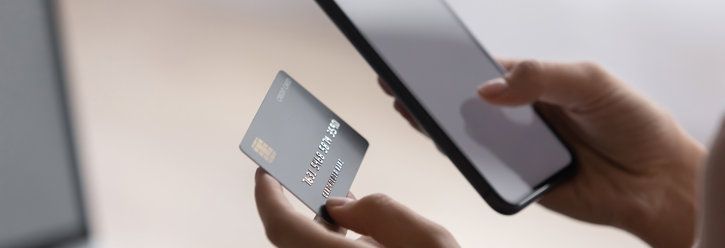 Women paying bill with credit card and mobile phone.