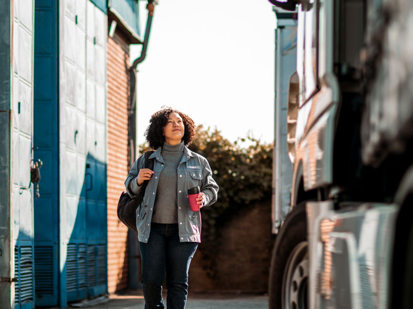 Female truck driver smiling and walking towards her truck to get ready to make a freight delivery.