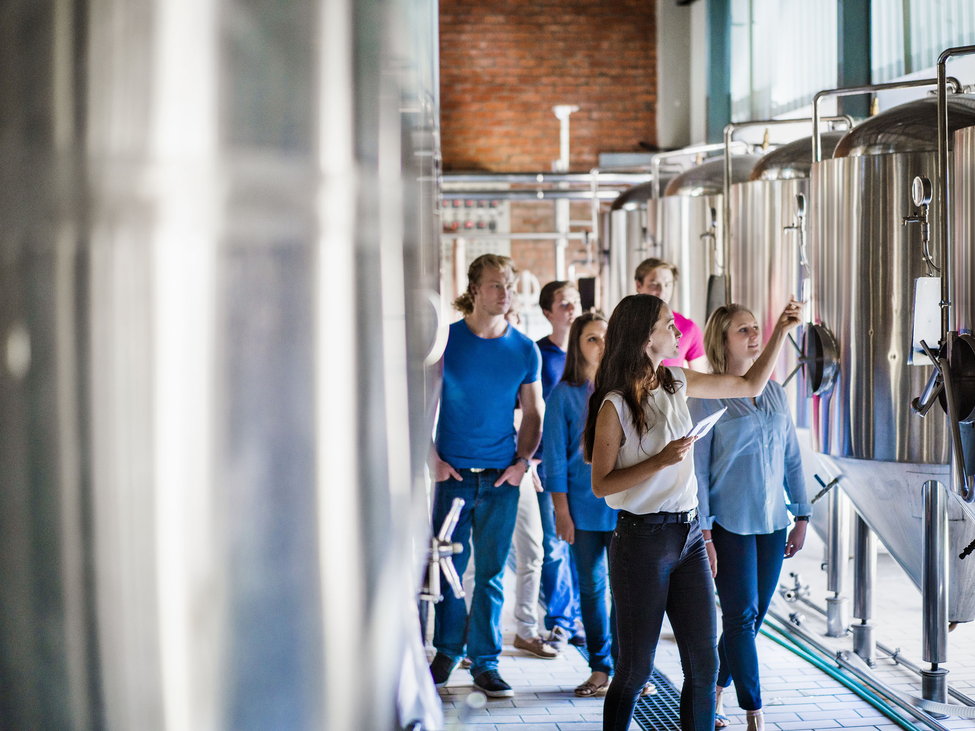 A group of adults on a tour of a craft brewing facility. 