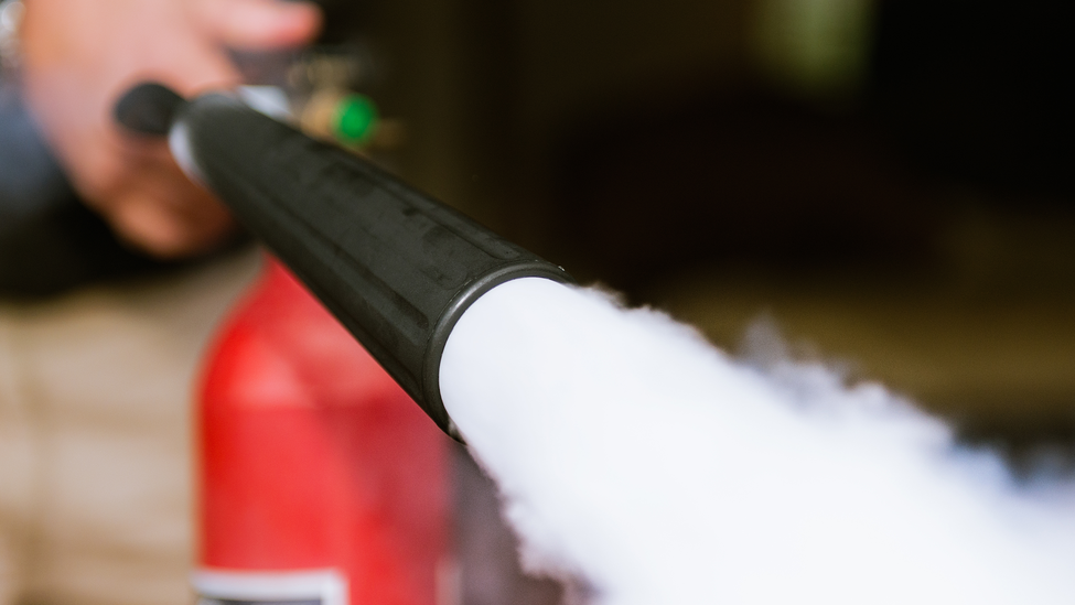 Close up taken as a man fires a carbon dioxide fire extinguisher.