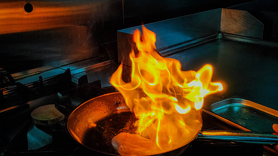 A small fire on a stove top that is contained within a frying pan.