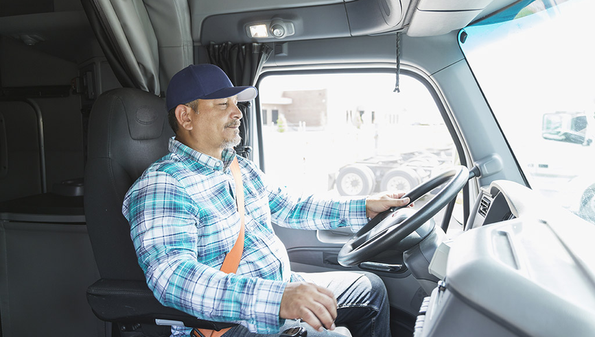 Photo of a truck driver at the wheel of a large commercial vehicle using ADAS technology.