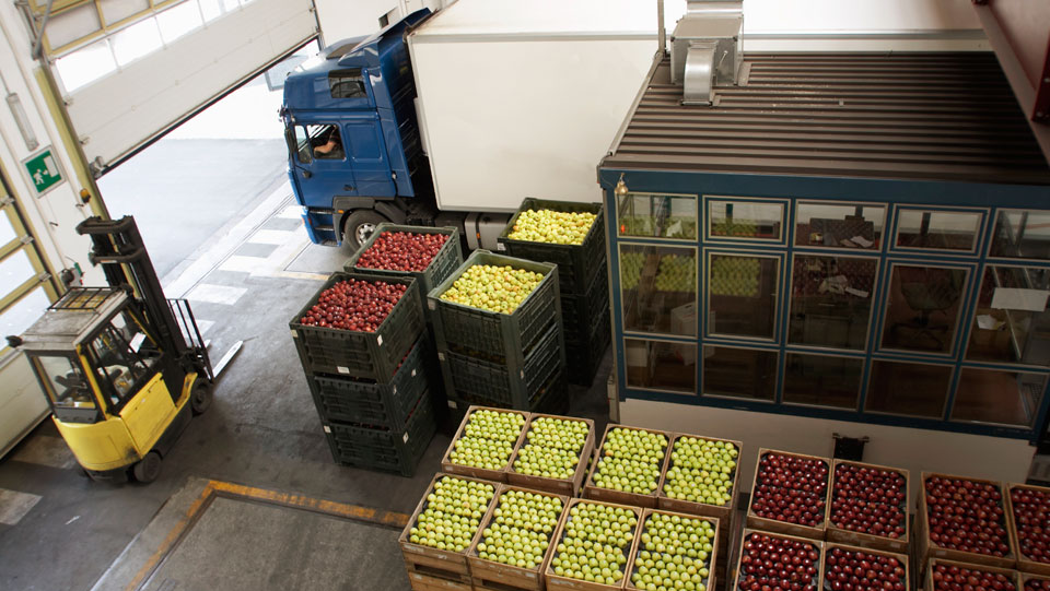 Truck driving next to open crates of fruit.