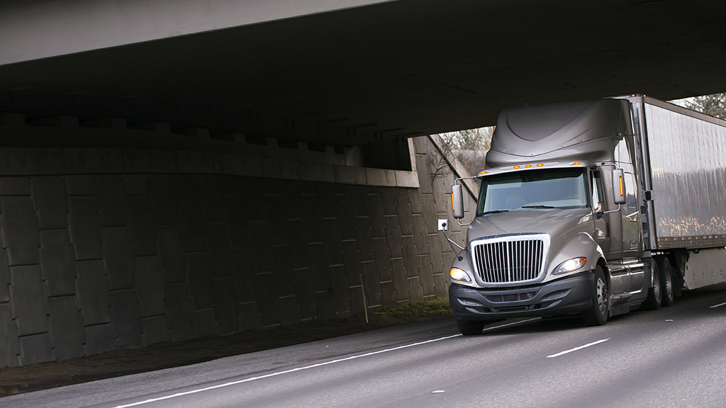 grey-truck-driving-underneath-bridge-large.jpg