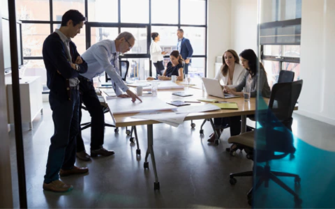 Group of people gathering around a table in an office building.