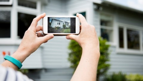 Person taking a picture of a home.