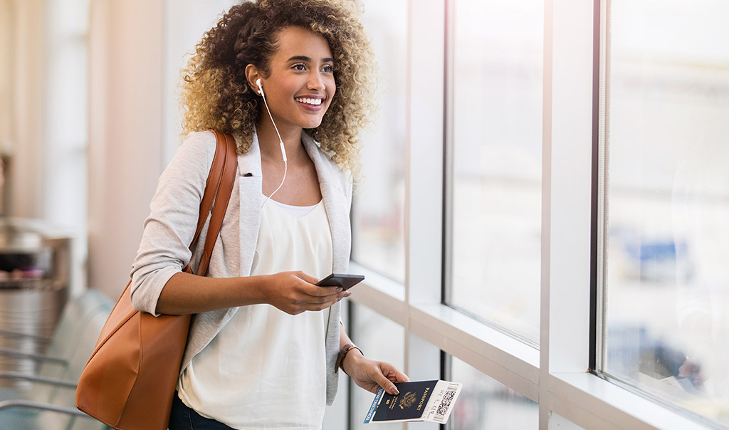 Woman standing at airport with passport in hand.