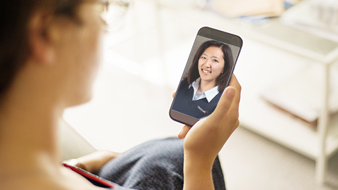 Customer holds their mobile phone while conducting a virtual visit with a Travelers representative.