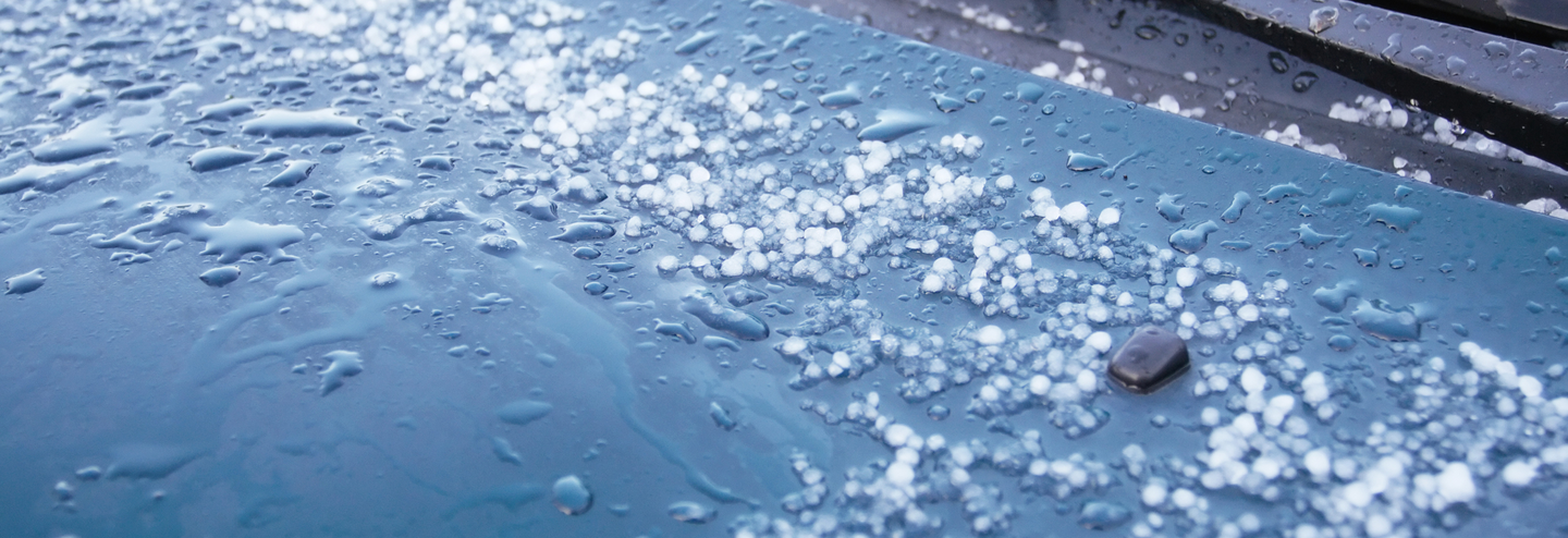 Just after a storm, an abstract view of hailstones starting to melt on the hood of this car.