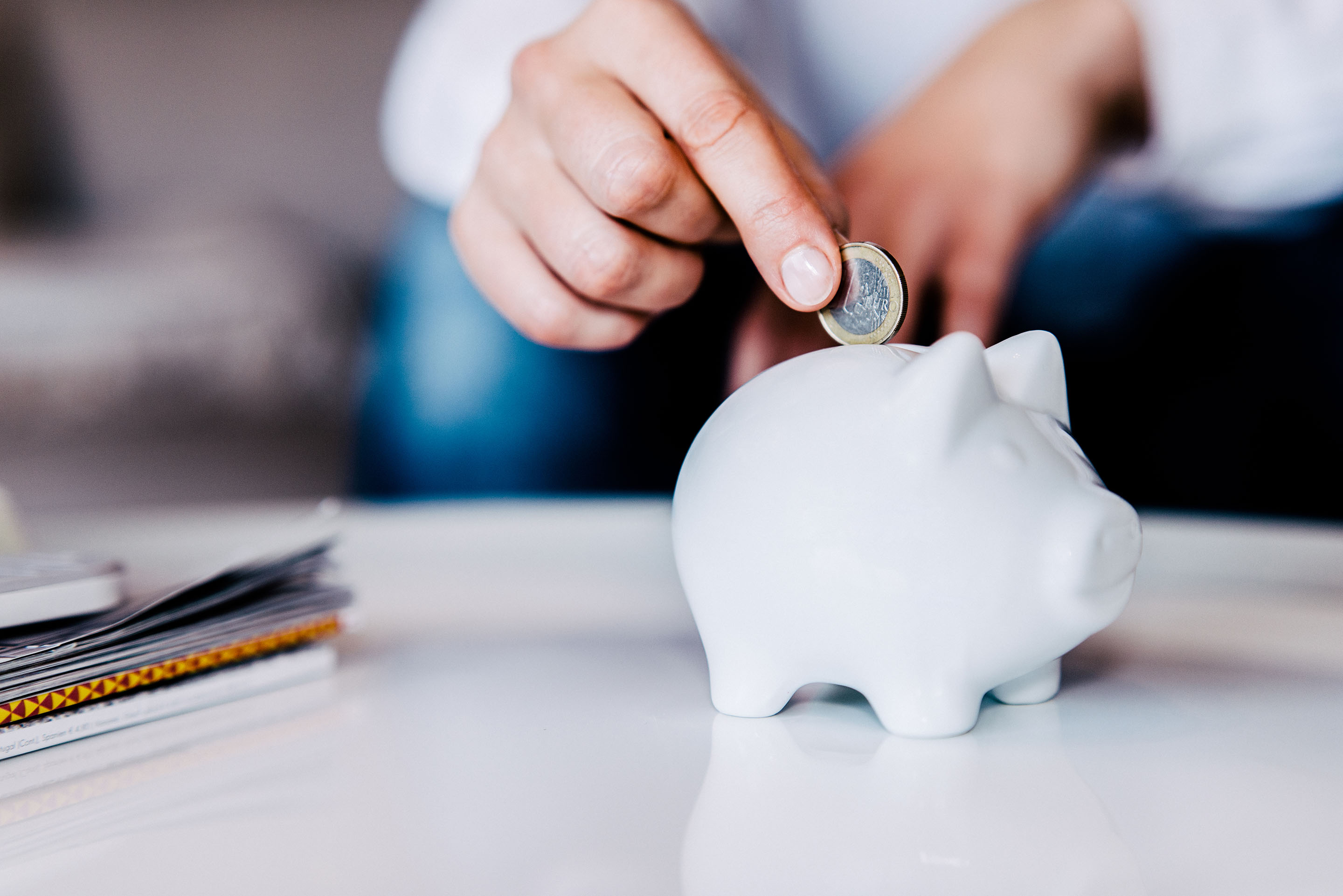 hand-putting-coin-in-white-piggy-bank.jpg