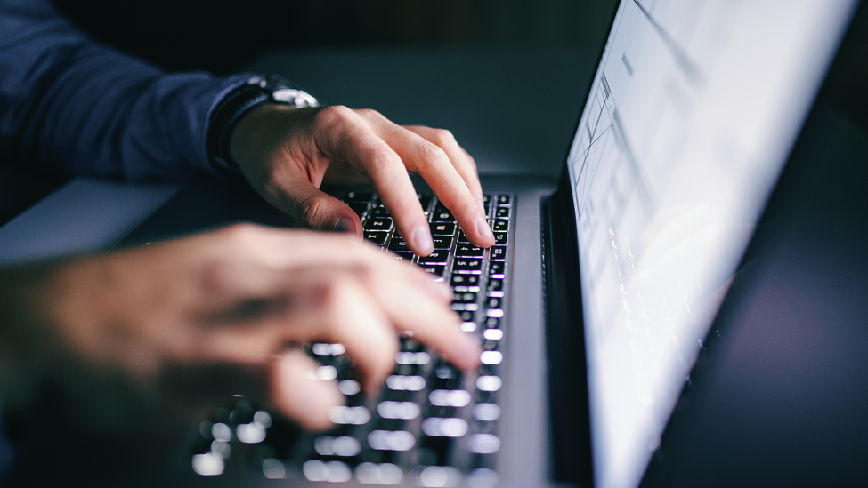 Close up of hands typing on laptop. Night work concept.