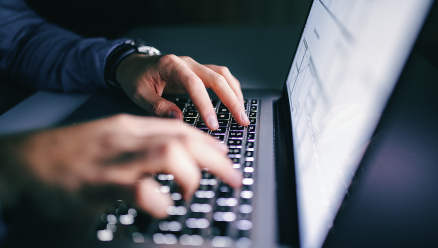 Close up of hands typing on laptop. Night work concept.