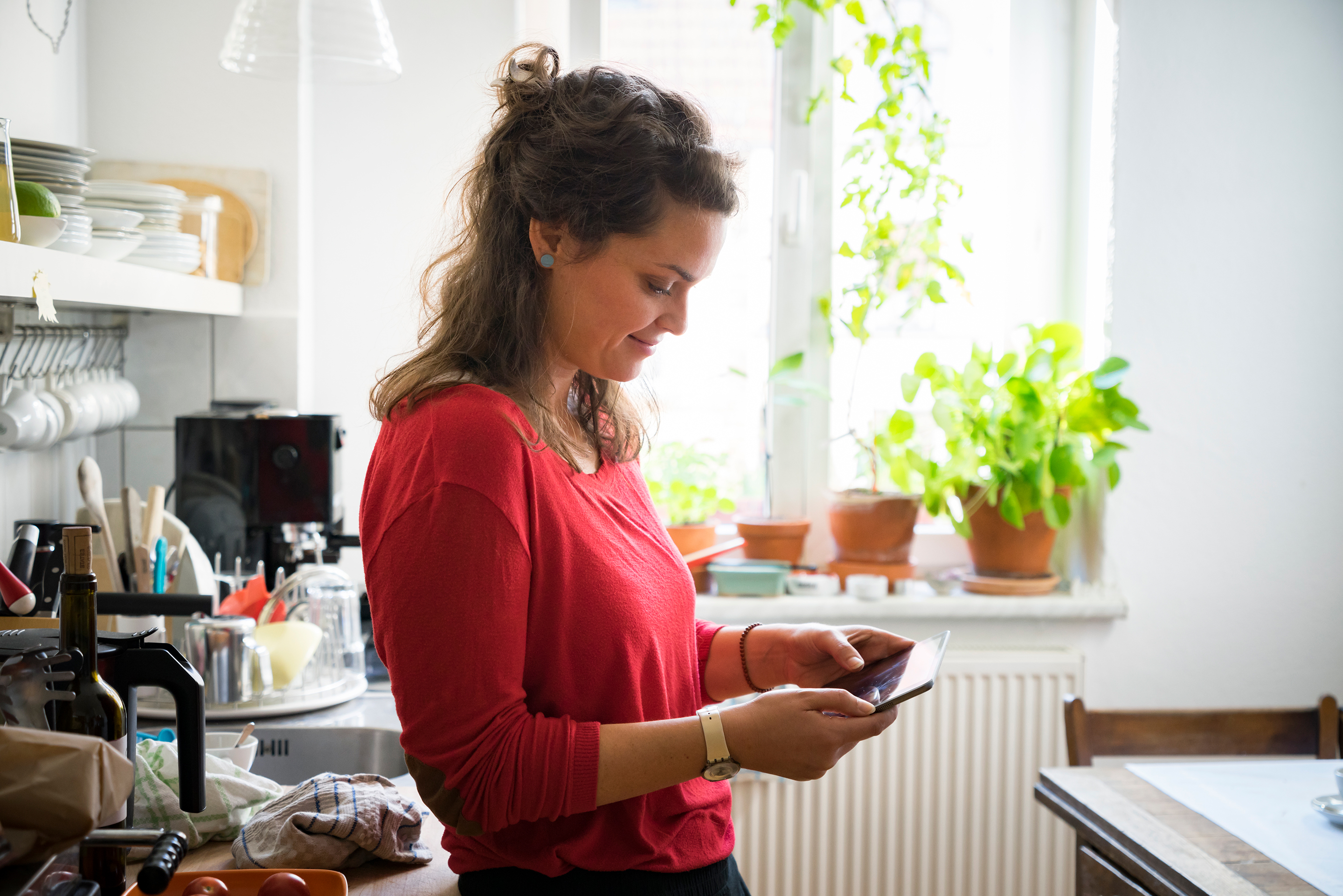 Individual looks through their insurance options on a tablet in their kitchen.