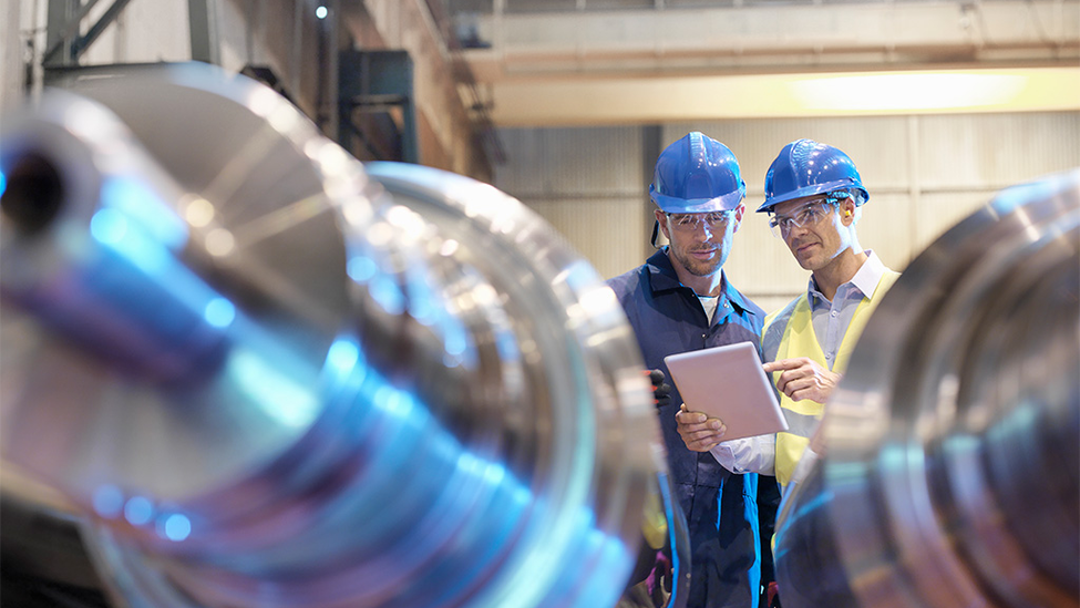 Two manufacturing engineer inspecting a big machine in a warehouse.