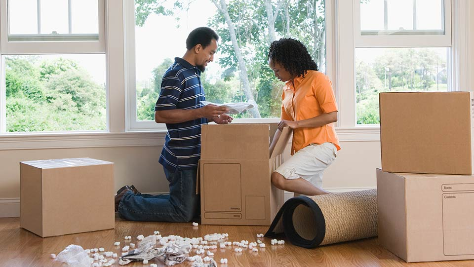 Couple in house packing boxes for a move.