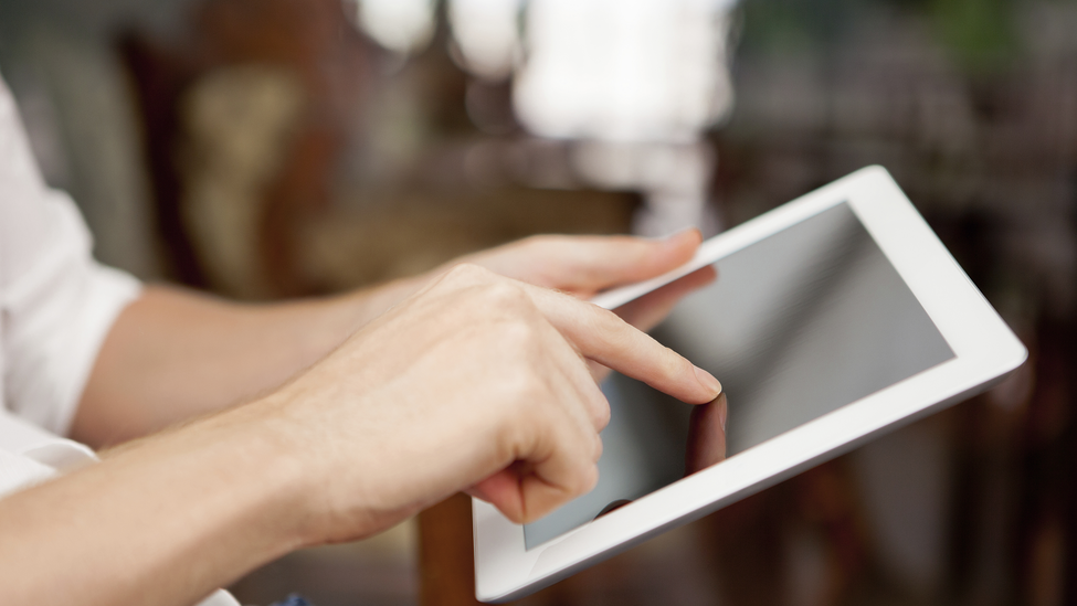 An individual navigates with a tablet PC to an online form.