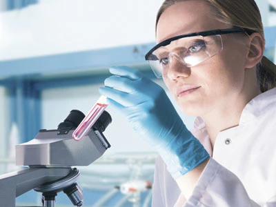 Scientist in white coat examining contents of vial.