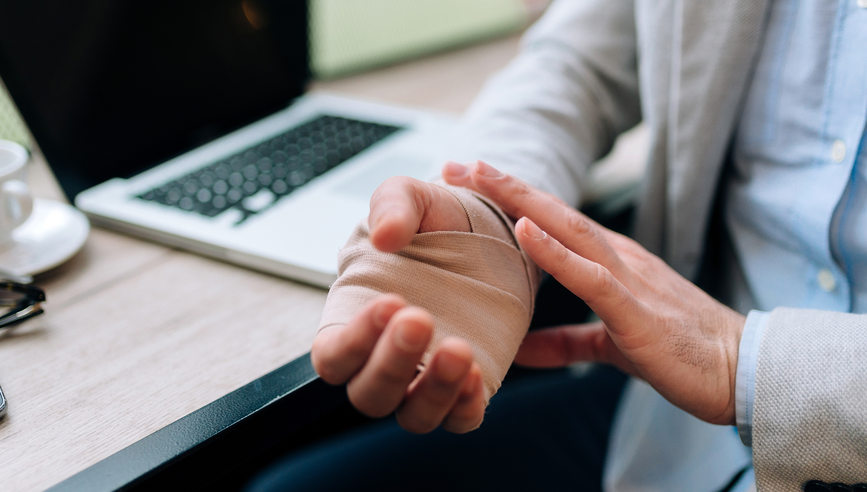 Injured worker with hand wraps using a laptop.