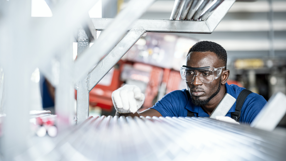 An inspector leans down to check mechanical metal equipment. 