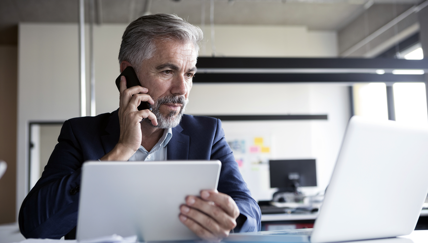 Insurance agent on a phone call looking at a laptop.