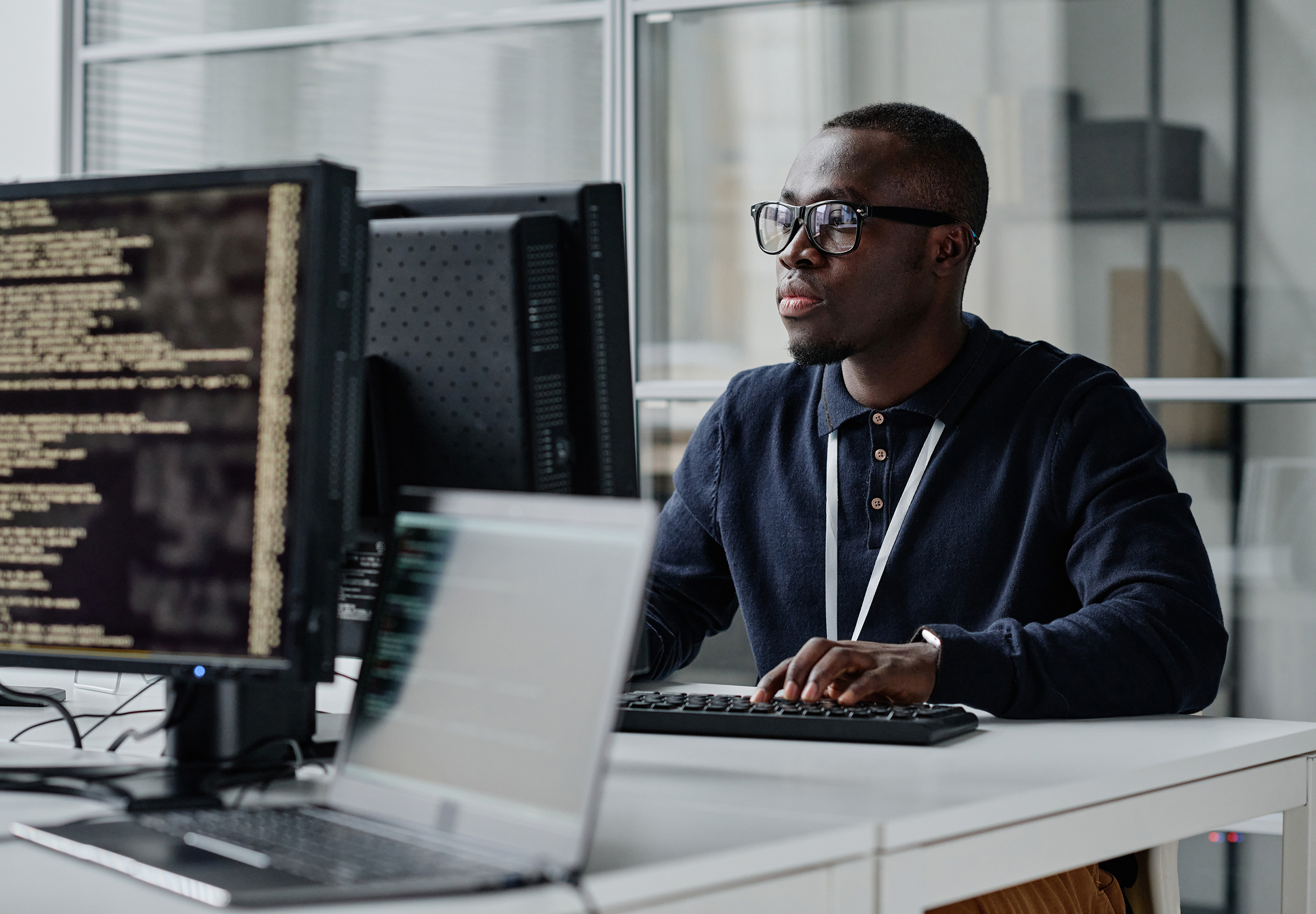 IT expert sitting at a desk in an office, working on a computer.