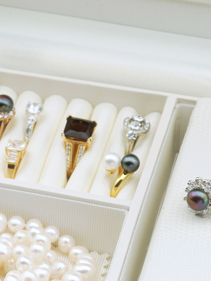 White jewelry box with engagement ring, pearls and other rings.