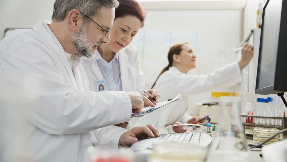 Group of doctors analyzing medical data at a computer in the laboratory.