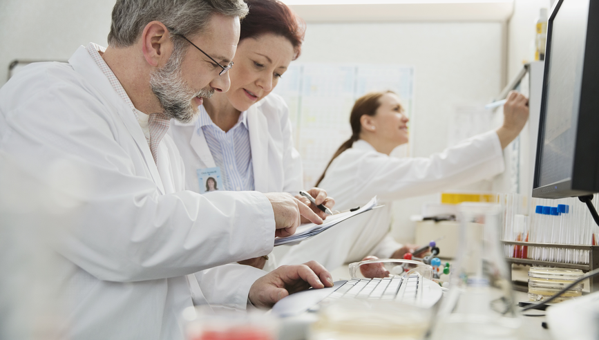 Group of doctors analyzing medical data at a computer in the laboratory.