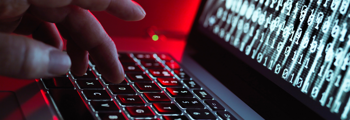 Laptop keyboard and screen showing a virus