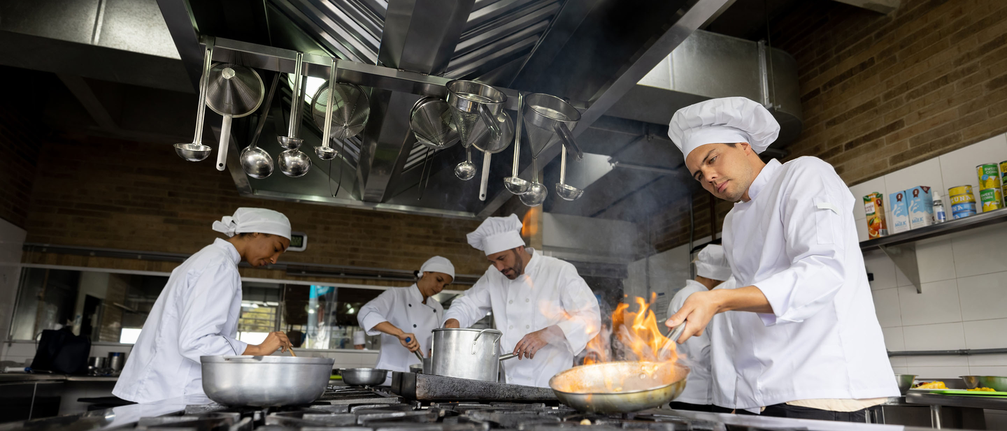 A group of chefs cooking food in a restaurant kitchen.