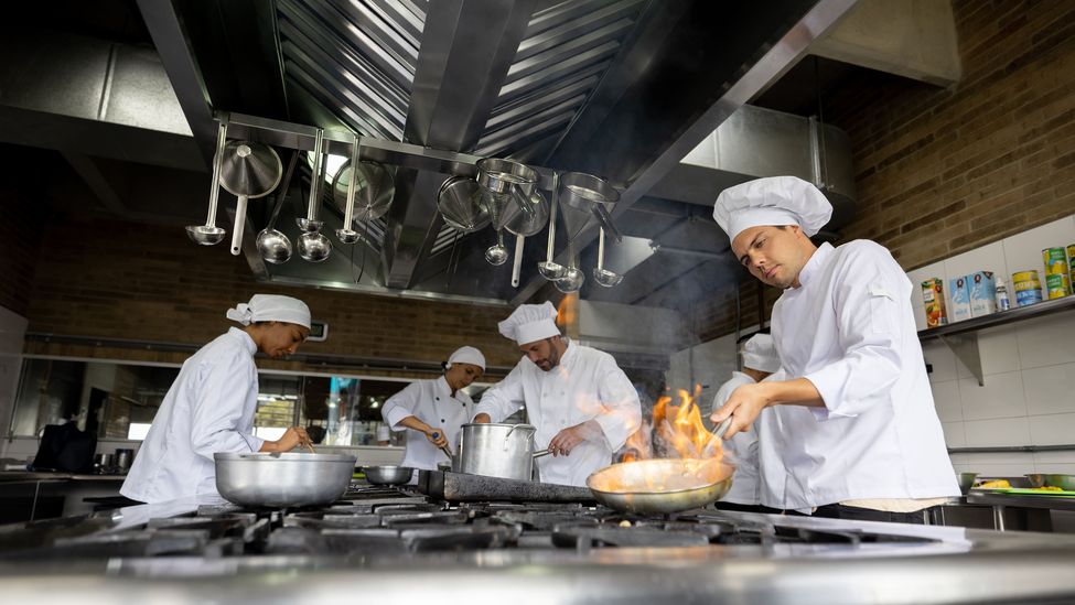 Chefs cooking food in a restaurant kitchen.