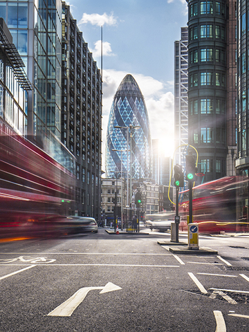 The Gherkin building in London shines at the end of the street.