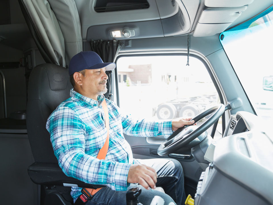 Male driver behind the wheel of a semitruck getting ready to make a delivery.