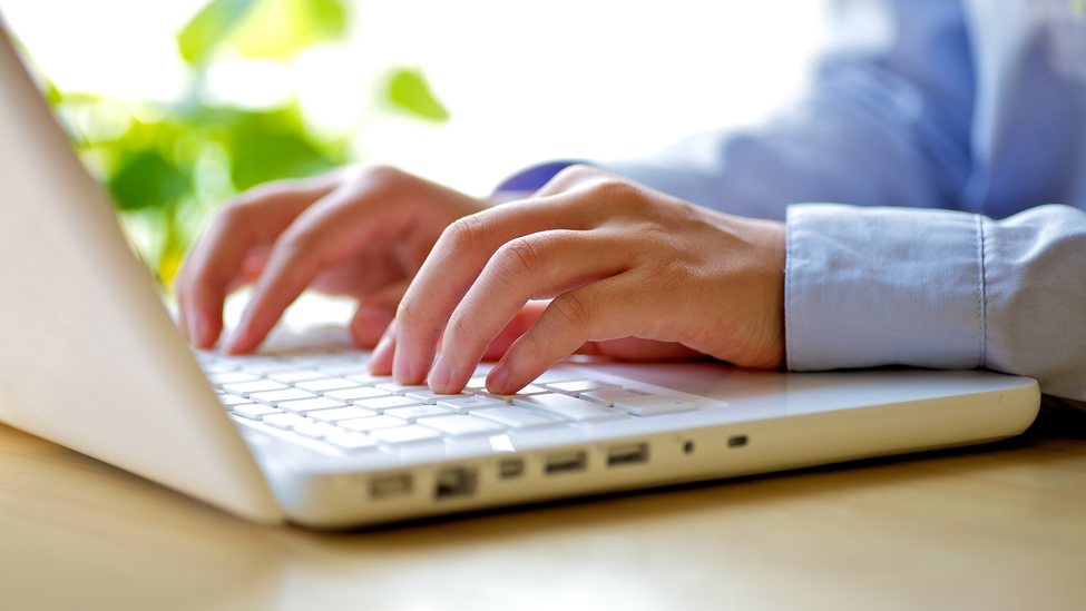 A businessman types on a laptop keyboard.