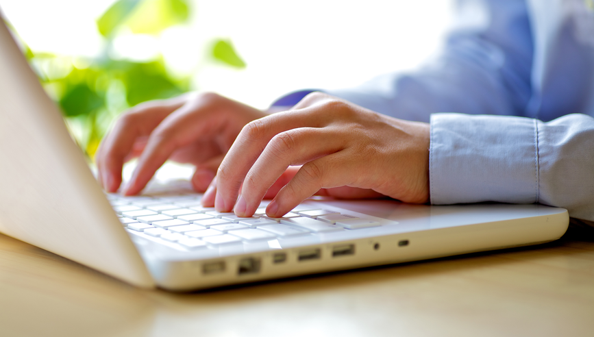 A businessman types on a laptop keyboard.