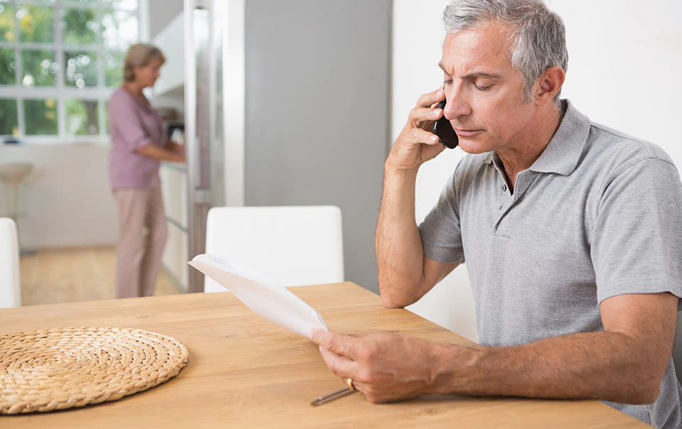 Male talking on phone with home insurance agent reporting a claim.