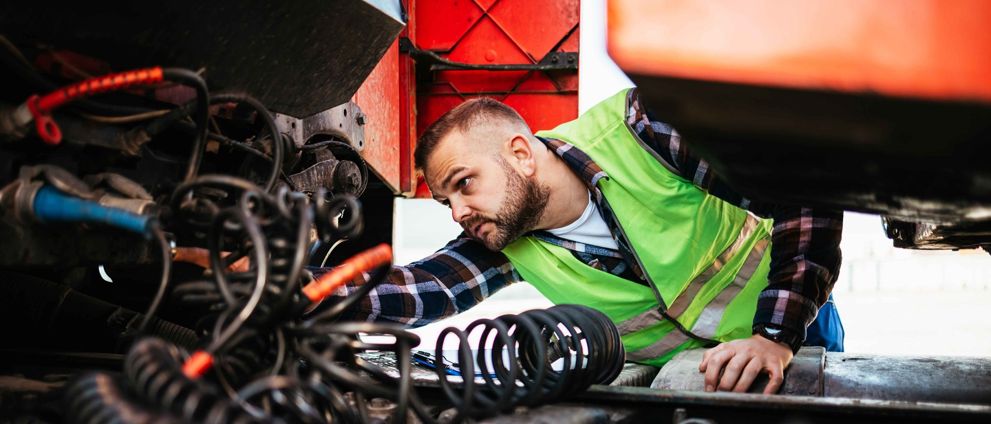 Male truck driver conducting a safety inspection on a truck.