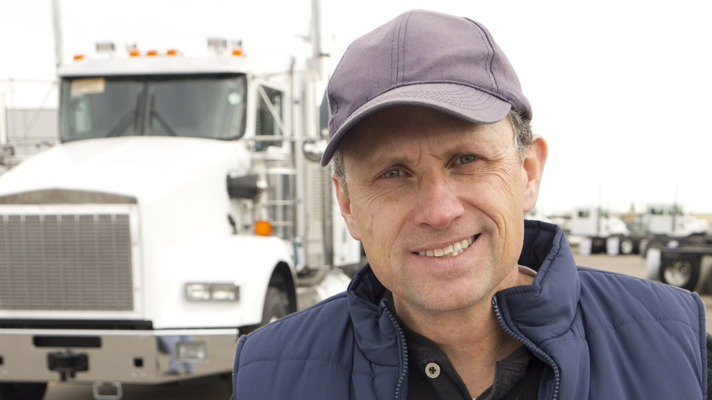 driver outside smiling next to a large commercial truck
