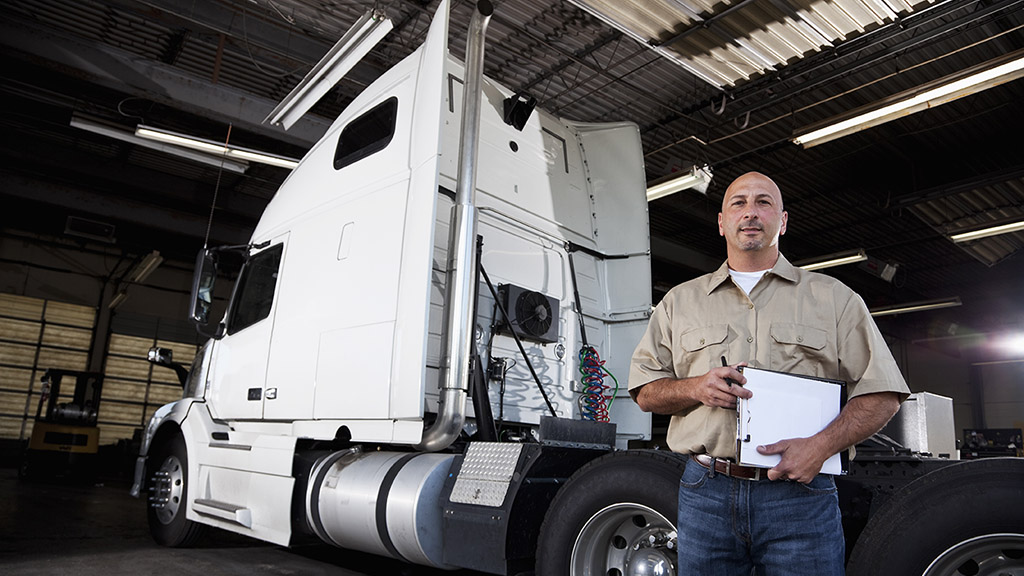 truck mechanic in a shop holding a clipboard